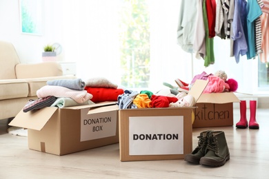 Photo of Donation boxes with clothes on floor in living room