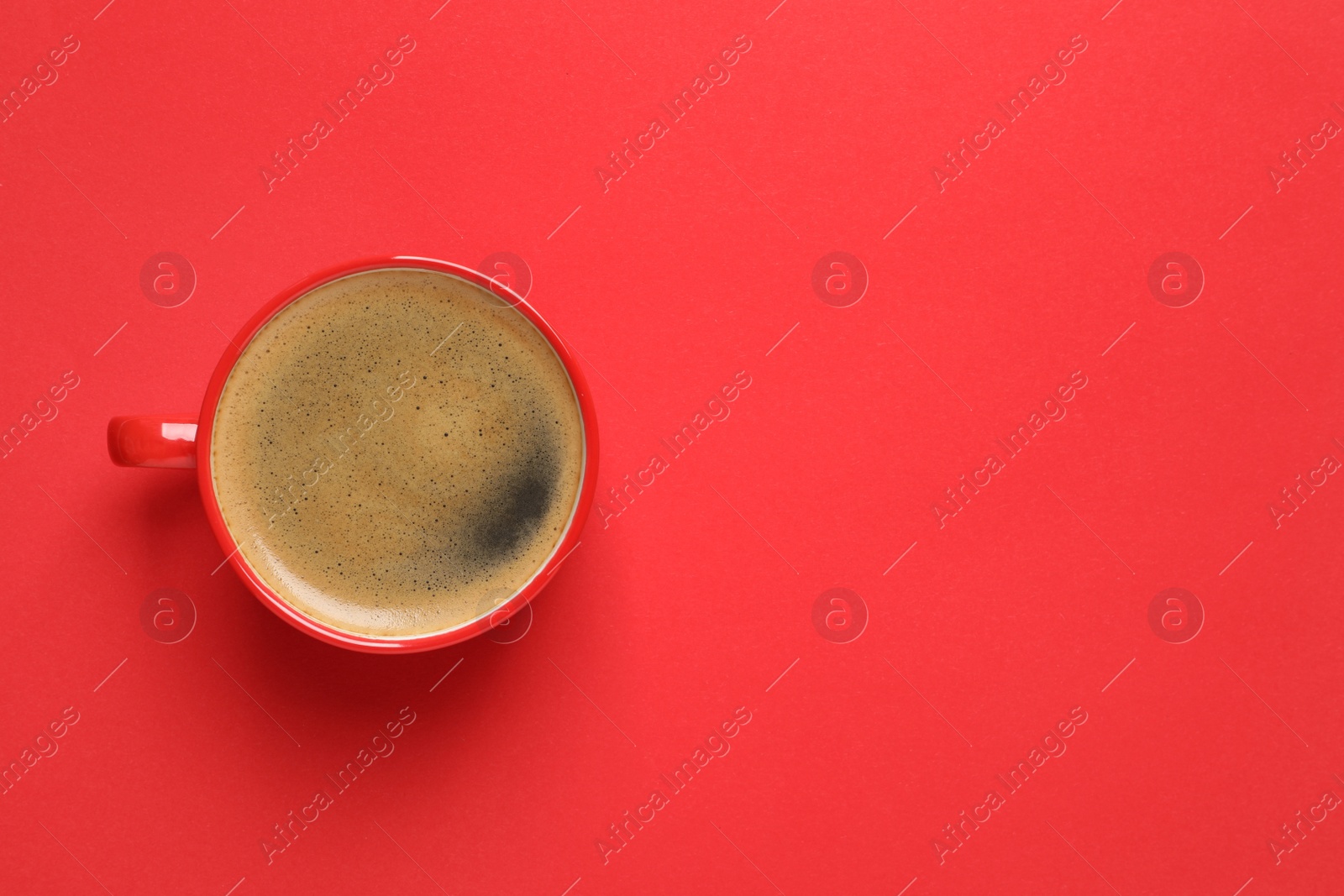 Photo of Cup of aromatic coffee on red background, top view. Space for text