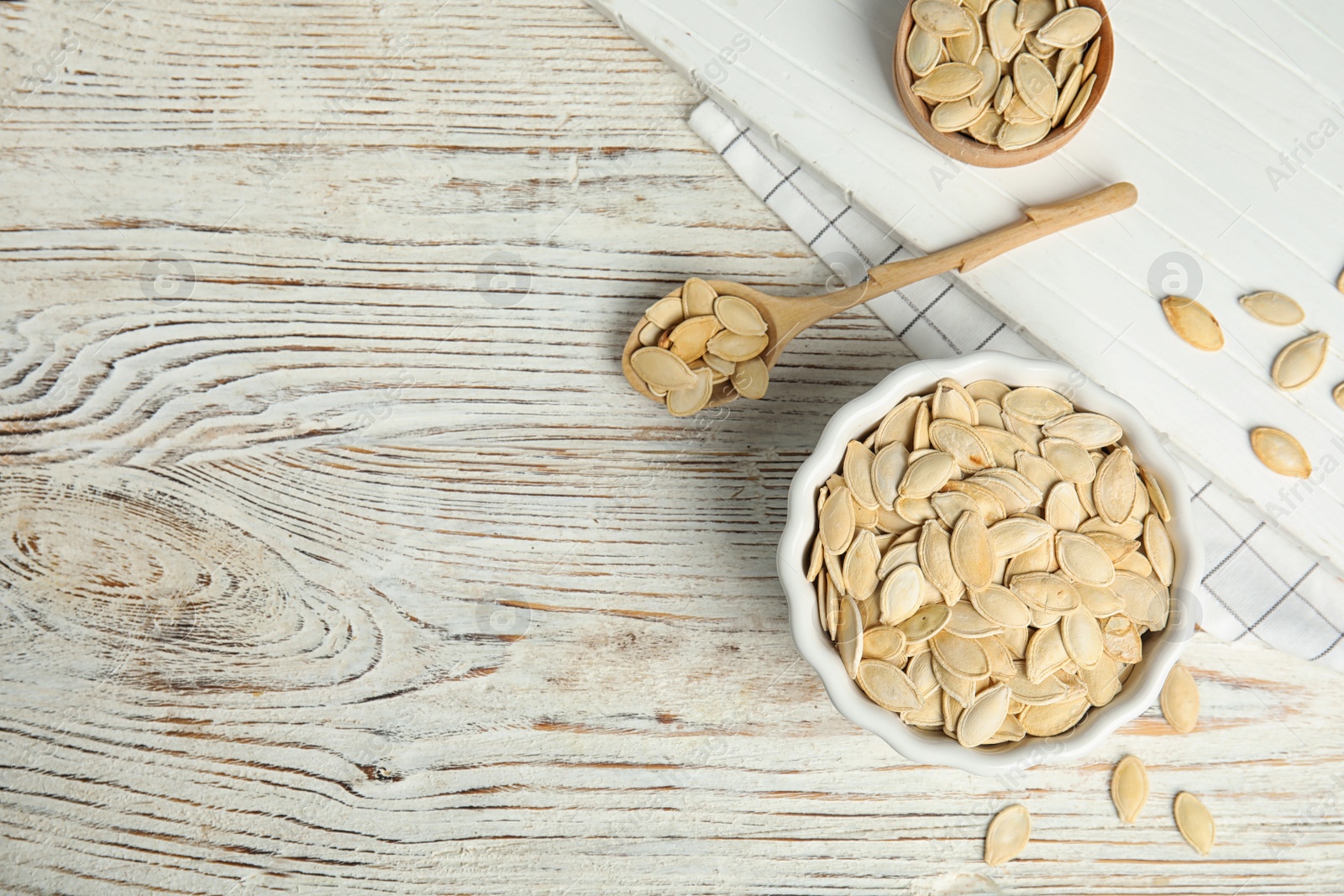 Photo of Flat lay composition with raw pumpkin seeds on white wooden table, space for text