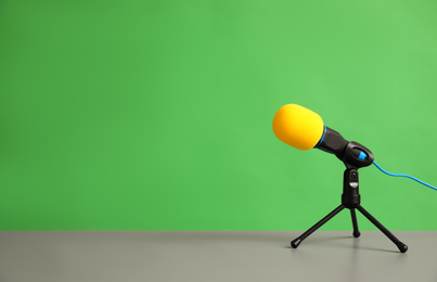 Microphone on table against green background, space for text. Journalist's work