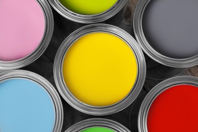 Photo of Cans of different paints on wooden table, flat lay