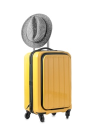 Photo of Bright yellow suitcase and hat packed for journey on white background