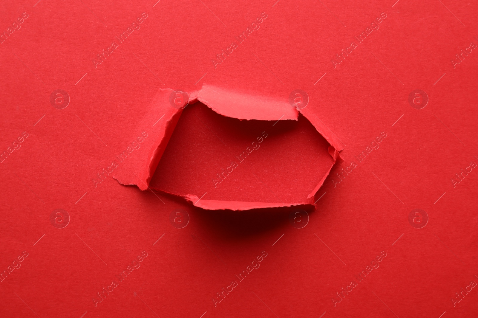 Photo of Hole in red paper on color background