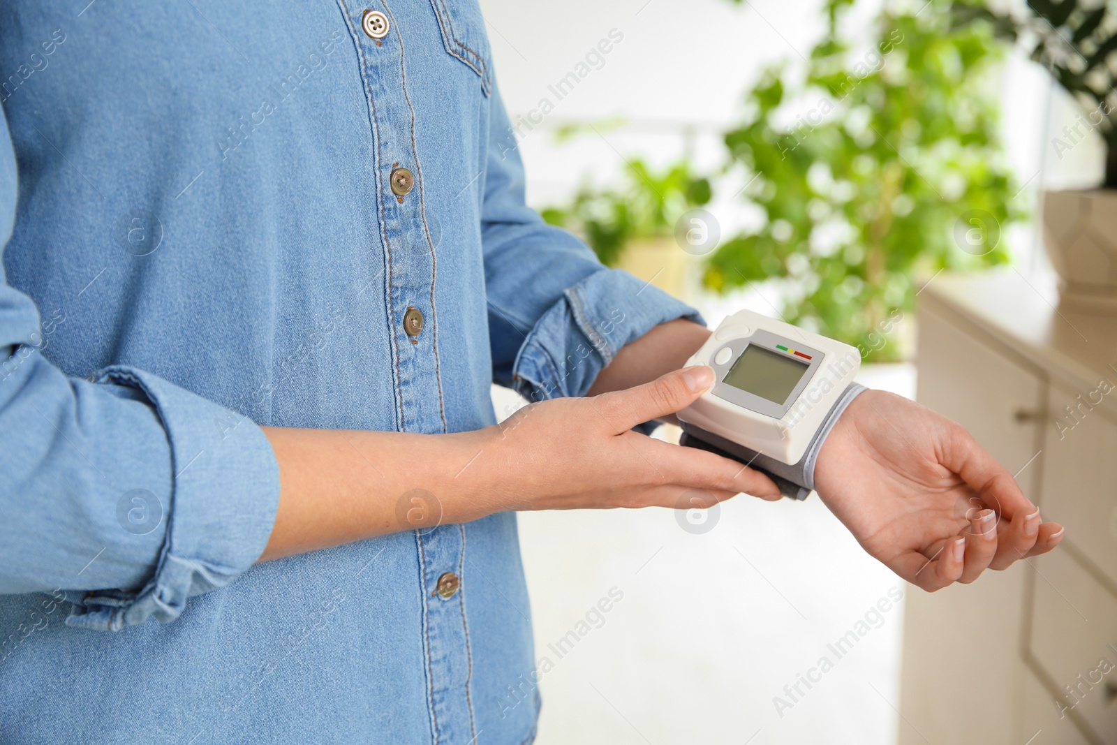 Photo of Young woman checking pulse with blood pressure monitor on wrist, closeup