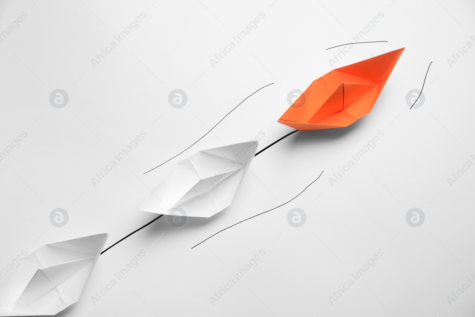 Photo of Group of paper boats following orange one on white background. Leadership concept