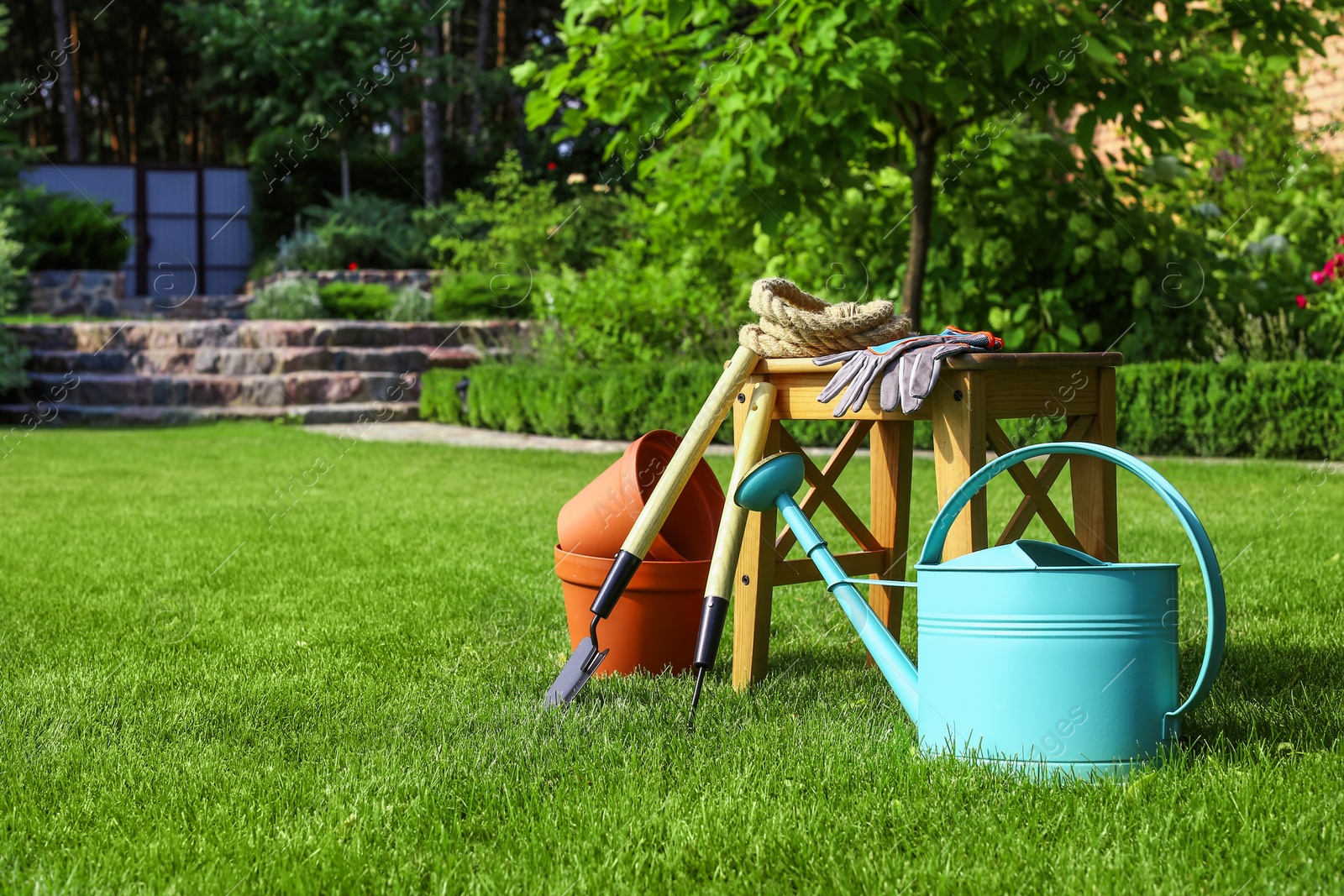 Photo of Set of gardening tools and stool on green grass