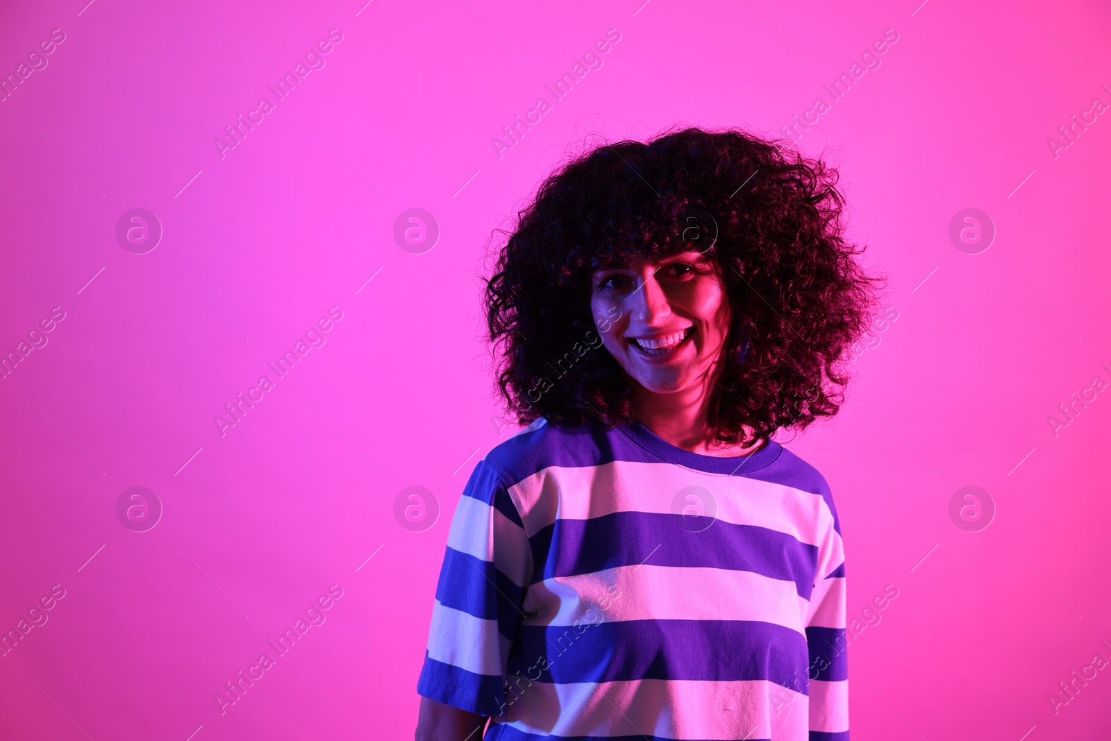 Photo of Beautiful young woman posing on color background in neon lights. Space for text