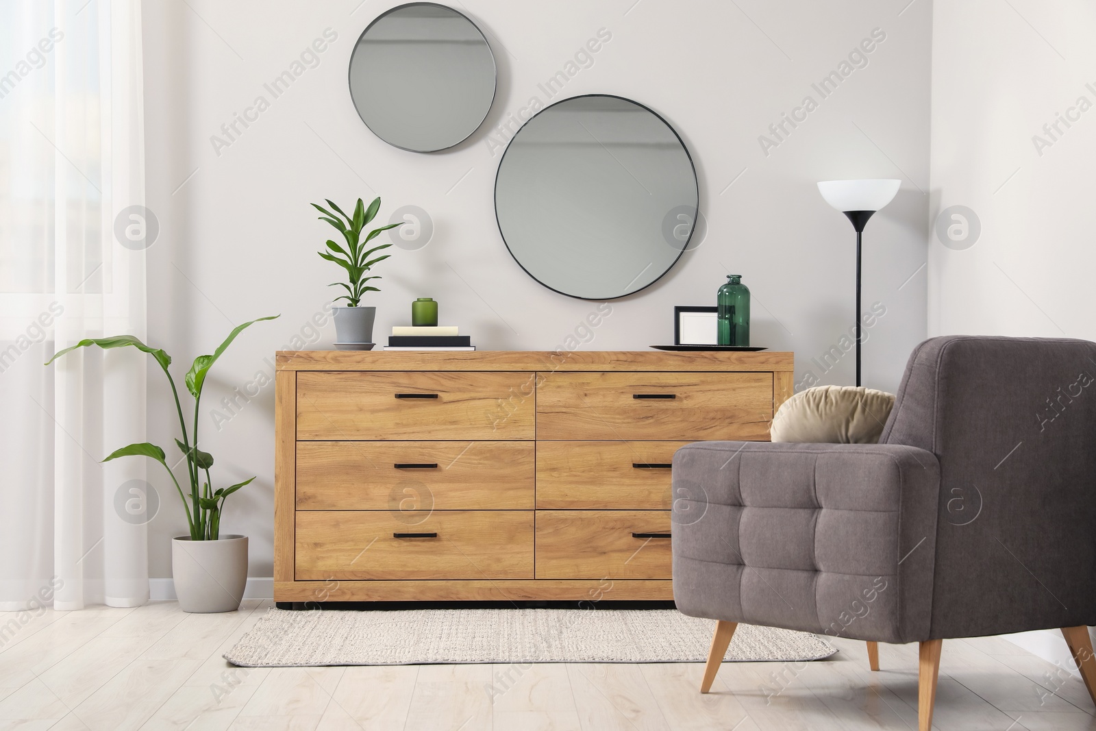 Photo of Cozy room interior with chest of drawers, mirrors, armchair and decor elements
