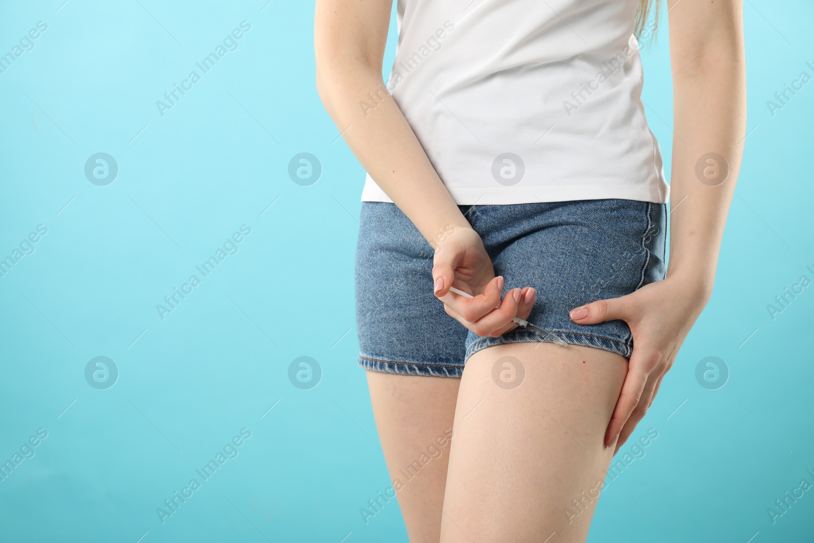 Photo of Diabetes. Woman making insulin injection into her leg on light blue background, closeup. Space for text