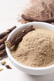 Photo of Powder and dried stick of liquorice root in bowl, closeup