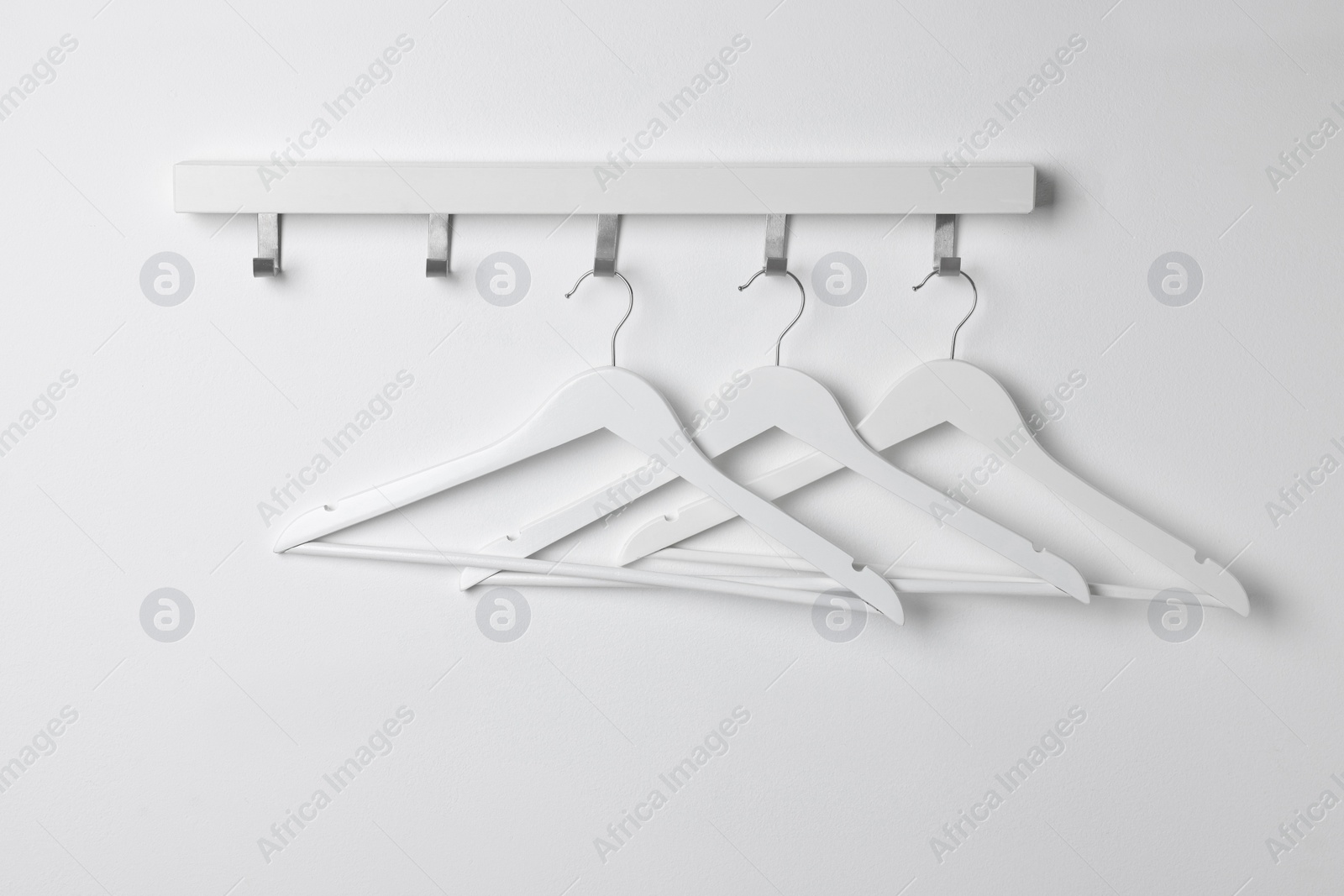 Photo of Rack with empty clothes hangers on white wall