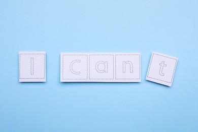 Photo of Motivation concept. Changing phrase from I Can't into I Can by removing paper with letter T on light blue background, flat lay