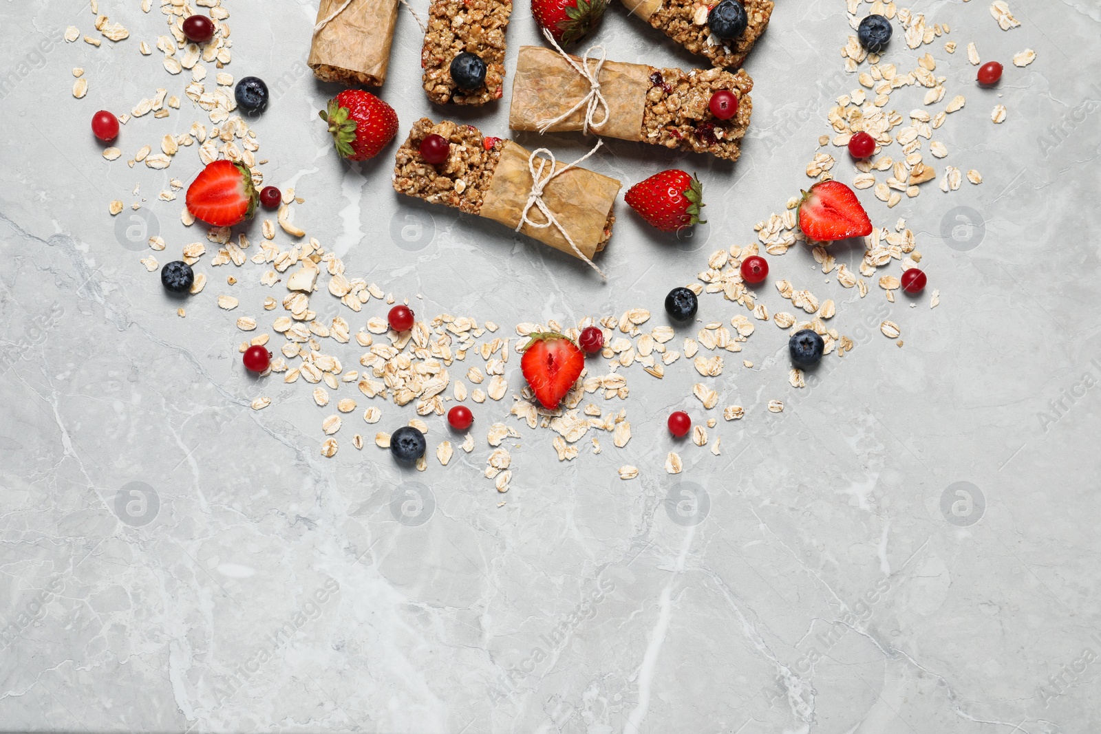 Photo of Tasty granola bars and ingredients on light grey marble table, flat lay. Space for text