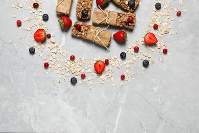 Tasty granola bars and ingredients on light grey marble table, flat lay. Space for text