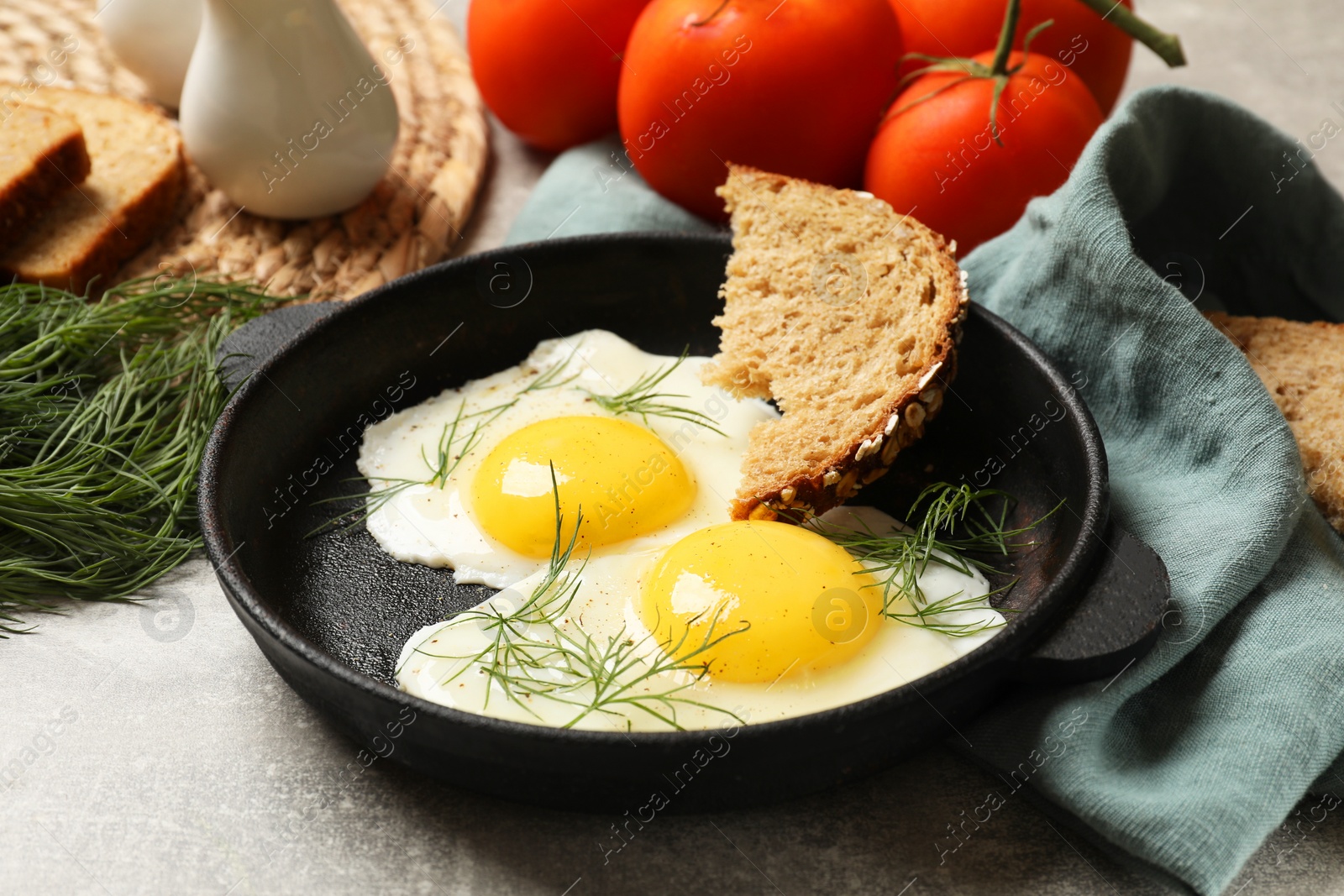 Photo of Delicious fried eggs served with bread on grey table