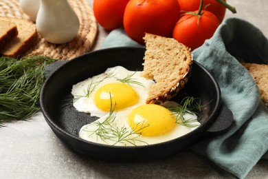Photo of Delicious fried eggs served with bread on grey table