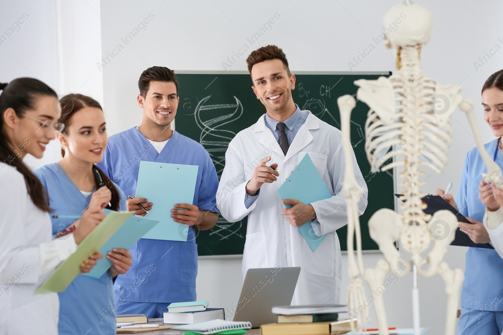 Photo of Medical students studying human skeleton anatomy in classroom