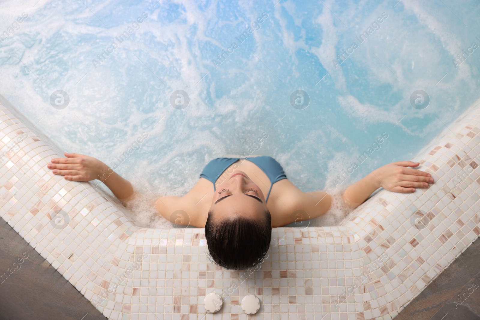 Photo of Beautiful woman relaxing in spa swimming pool, top view