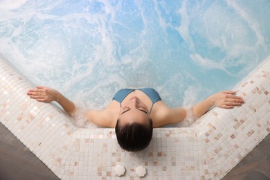 Photo of Beautiful woman relaxing in spa swimming pool, top view