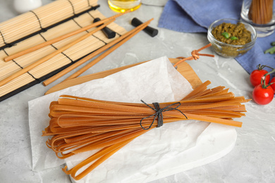 Tied uncooked buckwheat noodles on light grey table