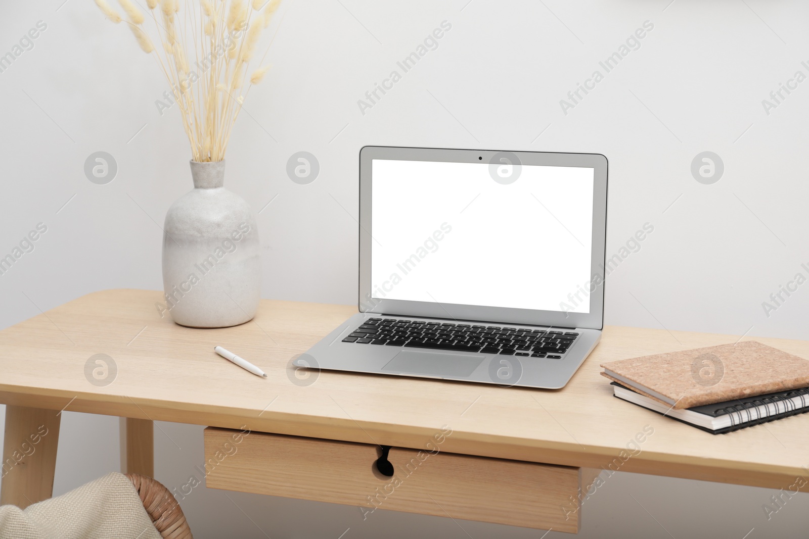 Image of Comfortable workplace at home. Modern laptop with blank screen and notebooks on wooden desk. Mockup for design