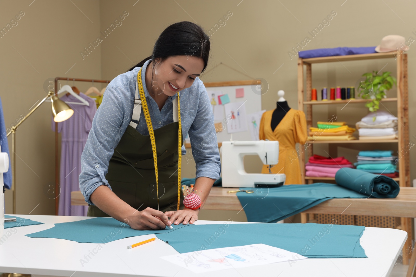 Photo of Dressmaker marking fabric with chalk in workshop