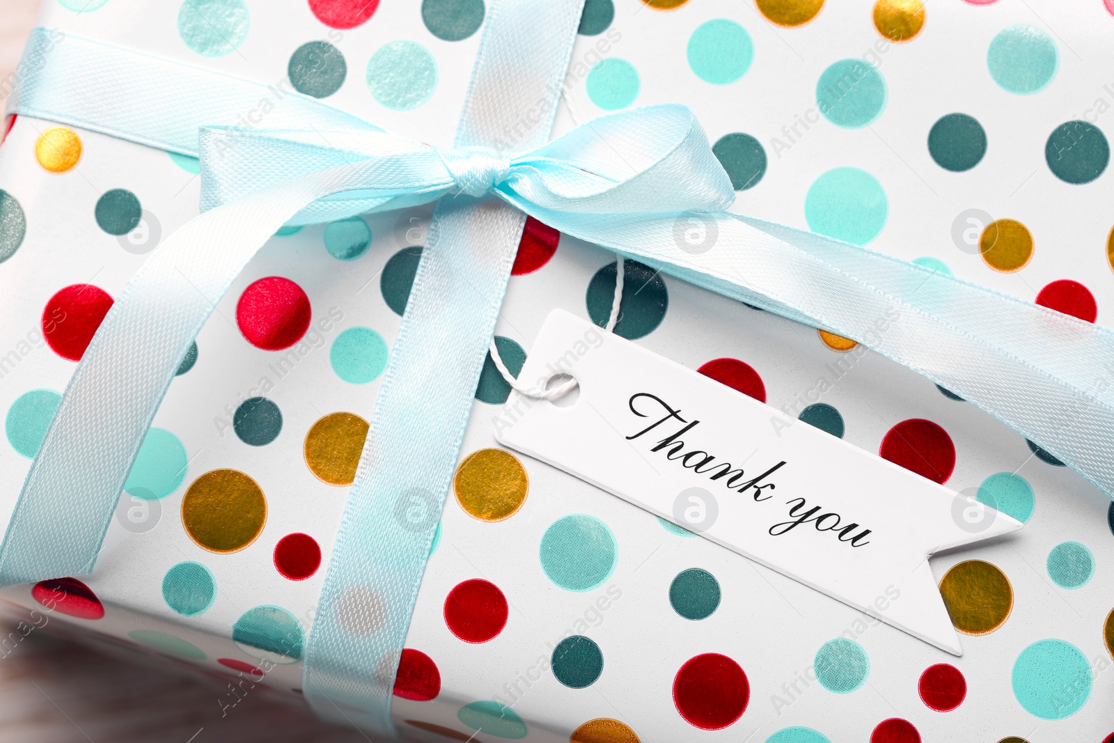 Photo of White tag with phrase Thank You on gift box, closeup