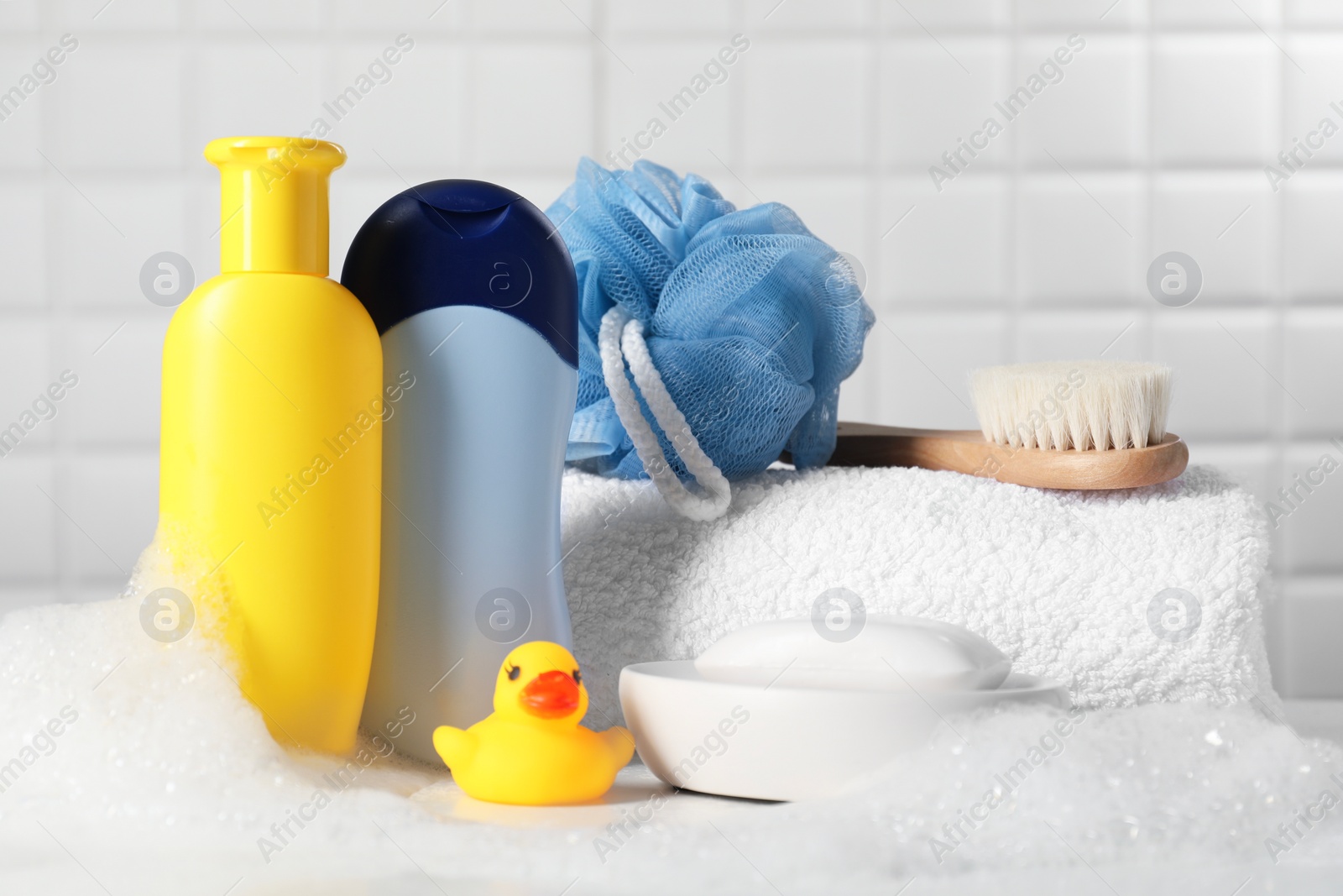 Photo of Baby cosmetic products, bath duck, brush and towel on white table