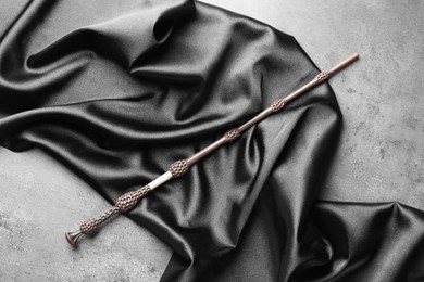 Photo of Magic wand and dark cloth on light grey background, top view