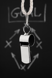 Photo of Referee whistle against chalkboard with game scheme, closeup