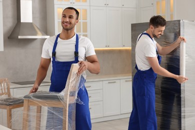 Photo of Male movers with chairs and refrigerator in new house