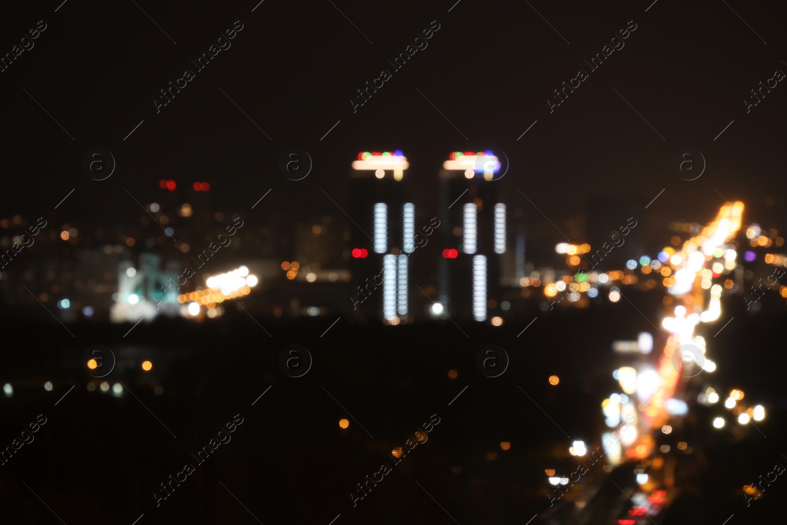 Photo of KYIV, UKRAINE - MAY 22, 2019: Blurred view of night city with apartment complex Soniachna Riviera and Metropolitan Andrey Sheptytsky Street, bokeh effect