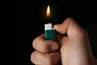 Man holding green lighter on black background, closeup