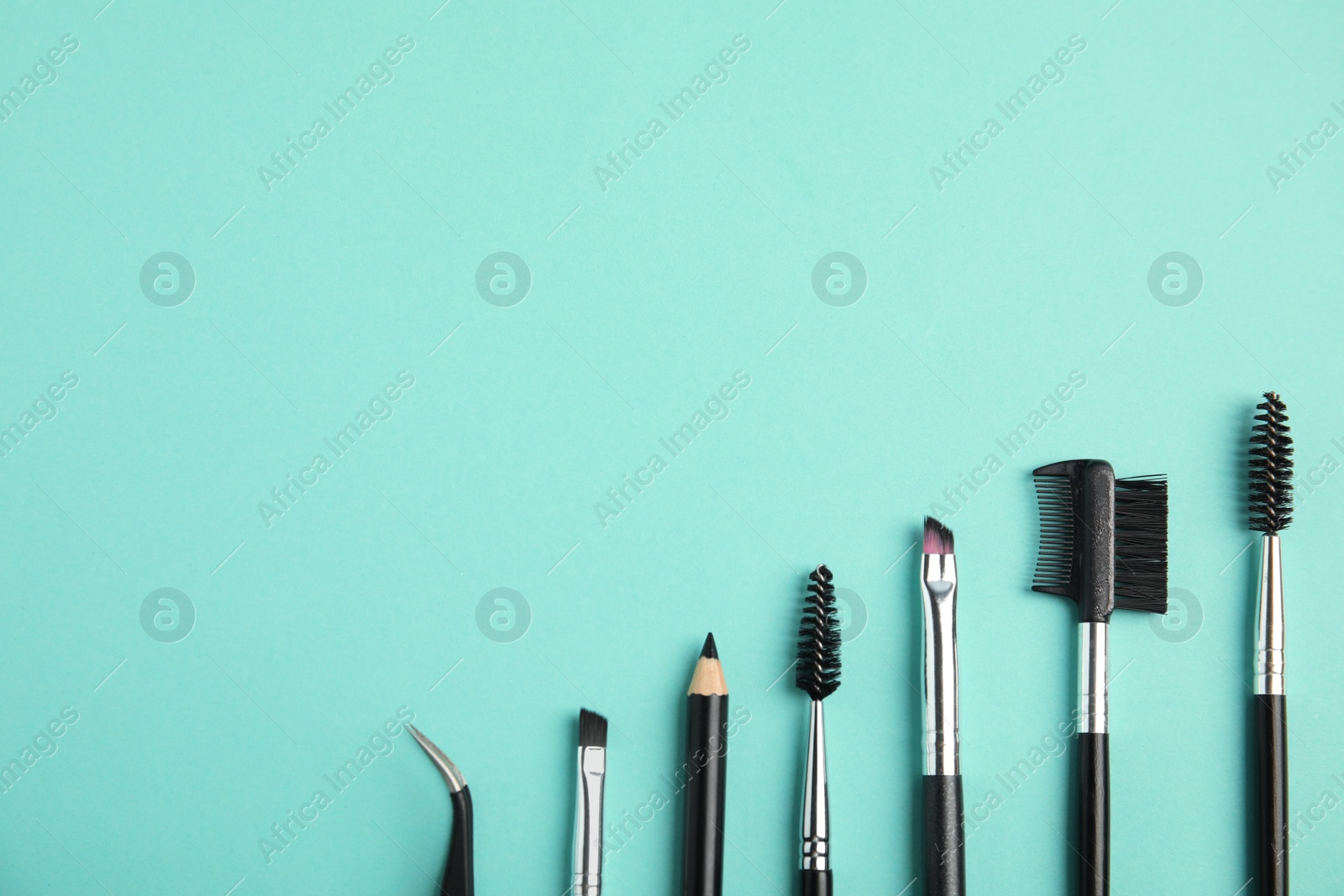 Photo of Set of professional eyebrow tools on turquoise background, flat lay. Space for text