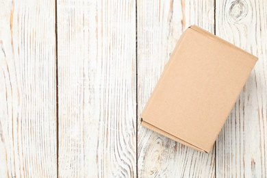 Photo of Cardboard box on white wooden background, top view. Space for text