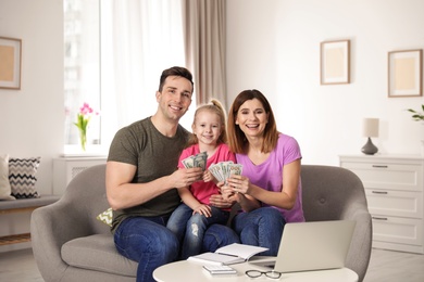 Happy family with money on sofa at home