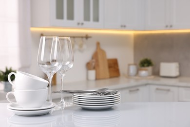 Photo of Set of clean dishware, glasses and cutlery on table in kitchen, space for text