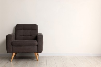 Comfortable armchair near white wall in room, space for text