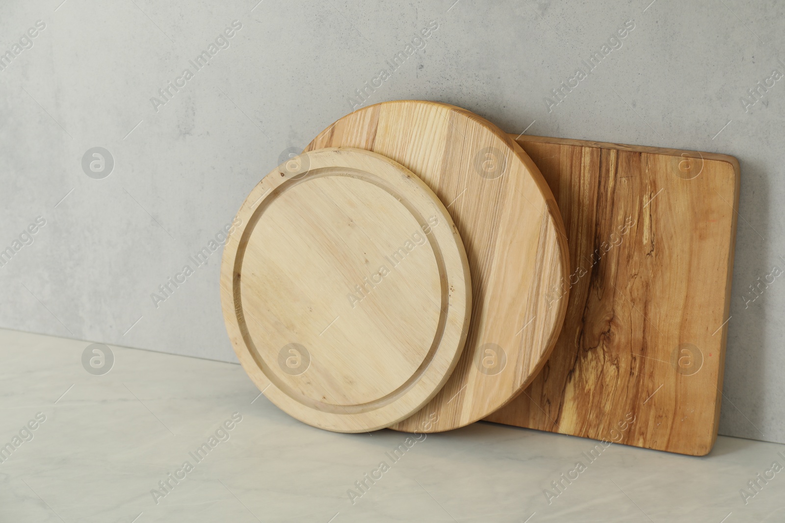 Photo of Different cutting boards on white table near light wall