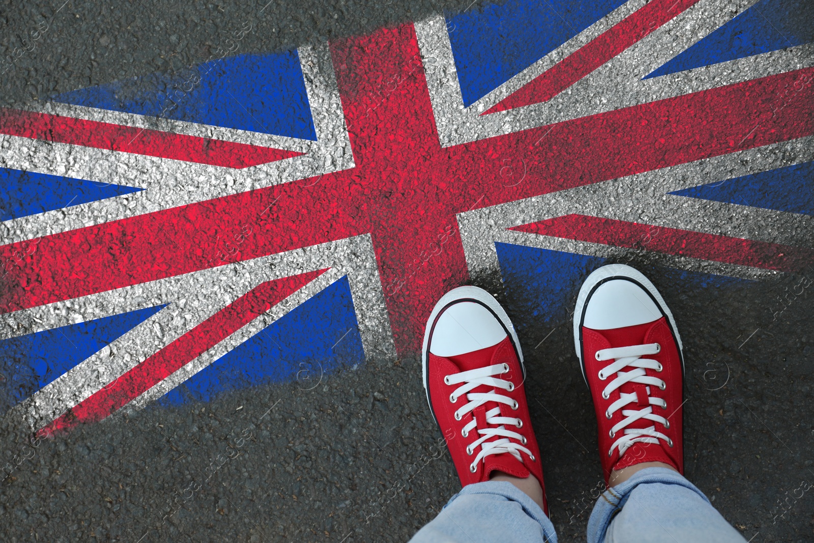 Image of Immigration. Woman standing on asphalt near flag of United Kingdom, top view