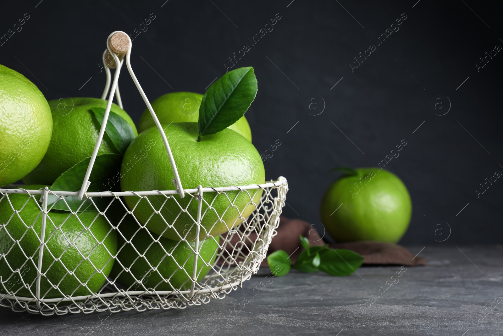 Photo of Fresh ripe sweeties in metal basket on grey table, space for text