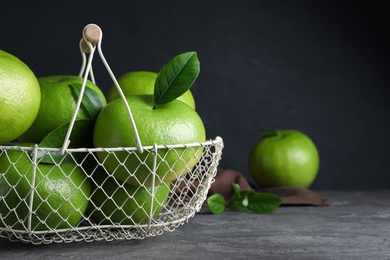 Fresh ripe sweeties in metal basket on grey table, space for text