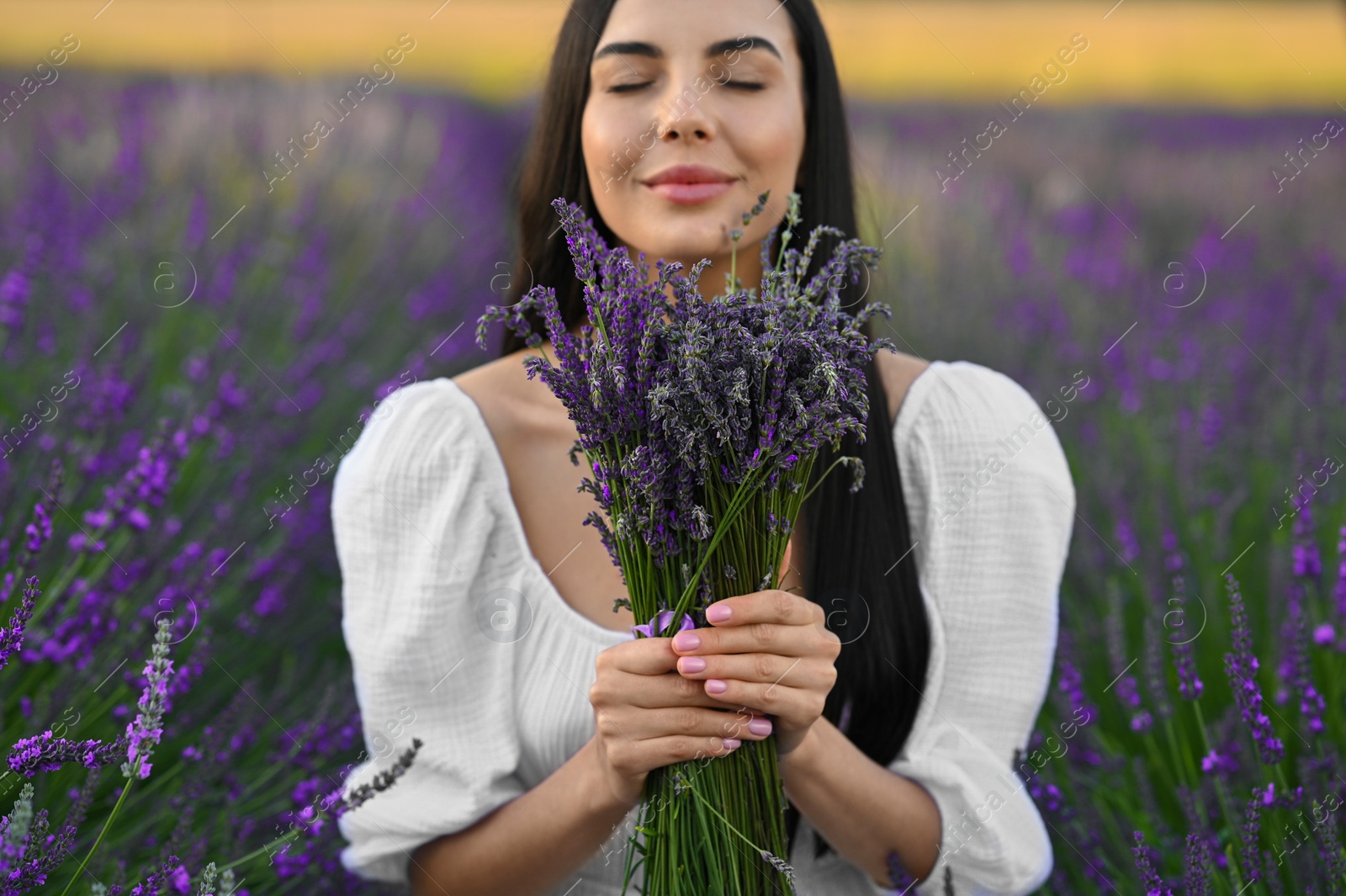 Photo of Beautiful young woman with bouquet in lavender field