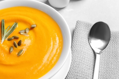 Photo of Bowl with tasty pumpkin soup served on table, closeup