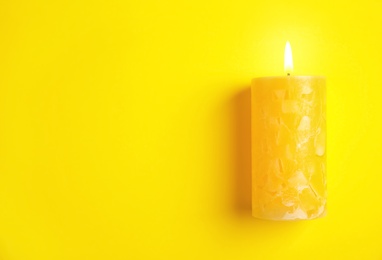 Alight wax candle and space for text on color background