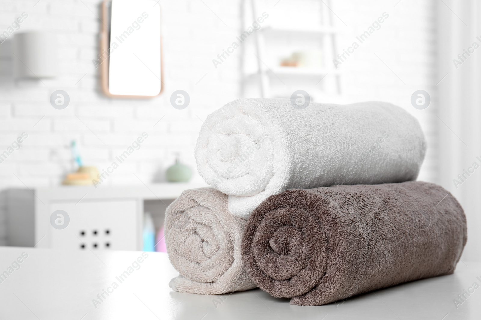 Photo of Rolled fresh towels on table in bathroom. Space for text