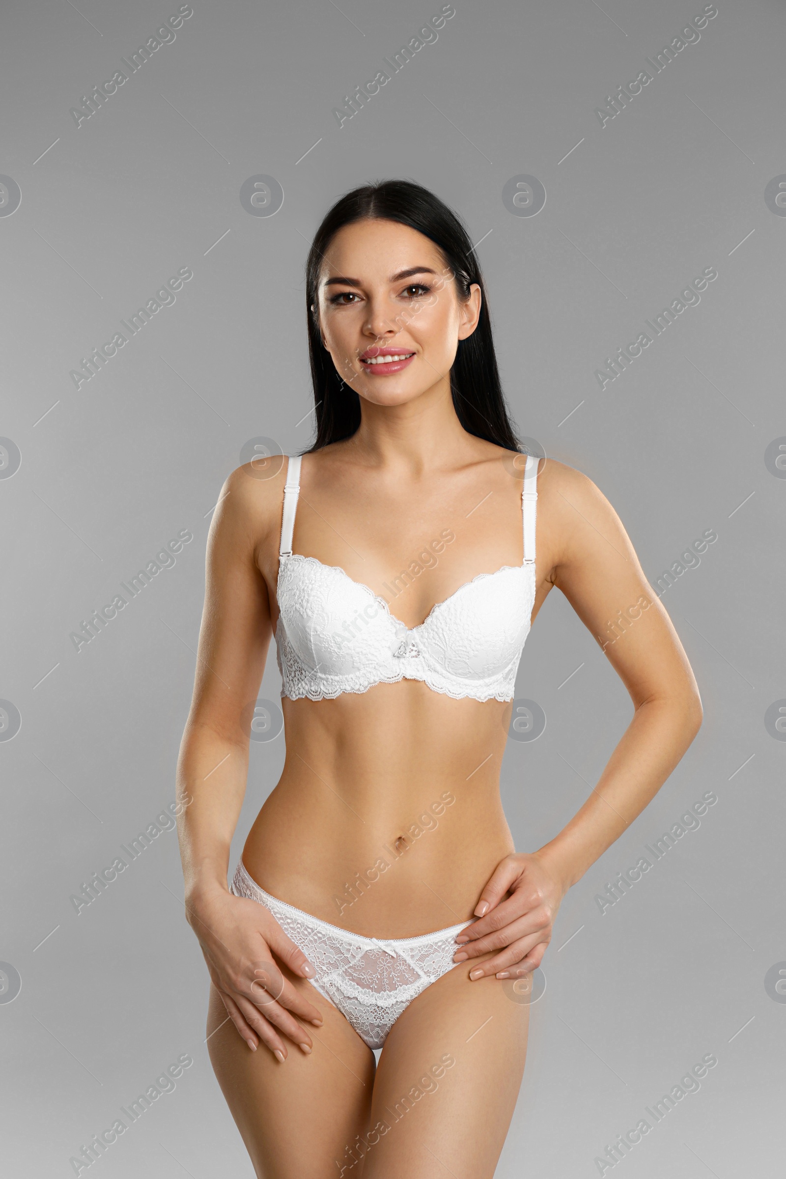 Photo of Beautiful young woman in white underwear on grey background