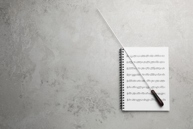 Photo of Conductor's baton and sheet music book on grey background, top view. Space for text