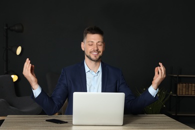 Businessman practicing zen yoga at table in office