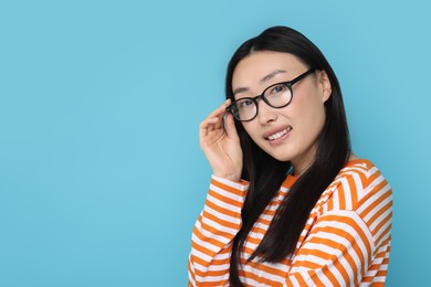 Portrait of happy woman in glasses on light blue background. Space for text